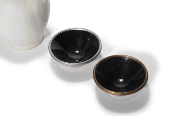 Castle AuctionA White Glaze Ewer and Two Black Glaze Tea Bowls with Metal Rims, 10th–13th C Pr.