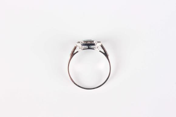TooveysA white gold, aquamarine and diamond cluster ring, collet set with the cut cornered rectangular step cut aquamarine within a surround of baguette and