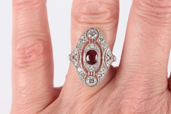 TooveysA platinum, ruby and diamond oval ring in an Art Deco inspired design, collet set with the oval cut ruby at the centre, detailed ‘Pt950’, weight 4.5