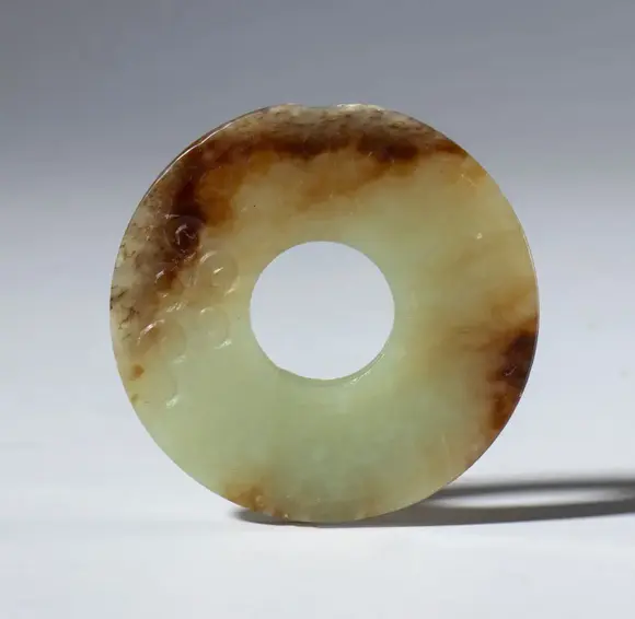 Bertolami Fine ArtA beautiful Bi disk in transparent jade with dark hues and small spiral carvings. China, Qing Dynasty (1644-1912), late 19th century.