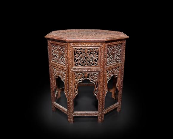 RoseberysAn octagonal carved wood table,?
Madras, India, mid-19th century

The table top fitting onto the hinged folding base, deeply carved to top with a