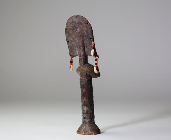 Goldfield Auction sarlsBambara / Marka, Afrique de l’Ouest.
Poupée sculptée, ornée de tissus rouges, de perles, de cauris et de 
plaques de métal gaufrées à décor de scar