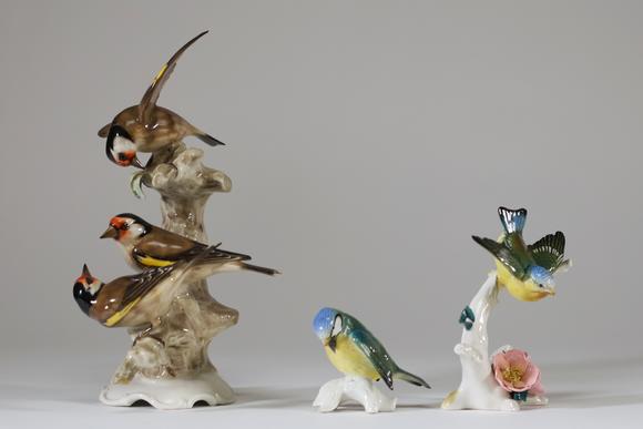 Goldfield Auction sarlsLot de trois sujets animaliers en porcelaine polychrome figurant des oiseaux branchés, comprenant un groupe de chardonnerets et deux petits oiseaux su