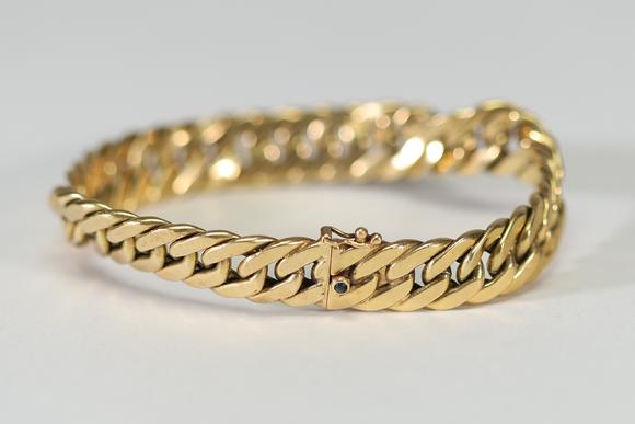 Goldfield Auction sarlsBracelet gourmette ? Caplain Paris ? en or jaune, composé de larges maillons plats et articulés, fermoir mousqueton orné d’un cabochon de saphir bleu