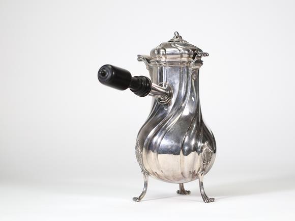 Goldfield Auction sarlsGrande chocolatière en argent massif reposant sur trois pieds cambrés, à décor de c?tes torses et appliques rocaille, bec verseur feuillagé, couvercle