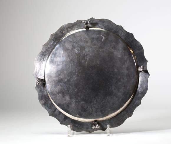 Goldfield Auction sarlsAssiette dite volante en argent massif, travail liégeois daté 1724, de forme circulaire à bord contourné et légèrement festonné. Elle repose sur trois