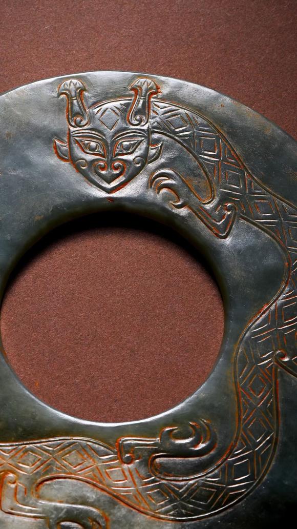 HUNG YUN ZHAI AUCTION HOUSE INCPre-Ming Dynasty Cinnabar-Infiltrated Dragon- Pattern Jade Bi Disc