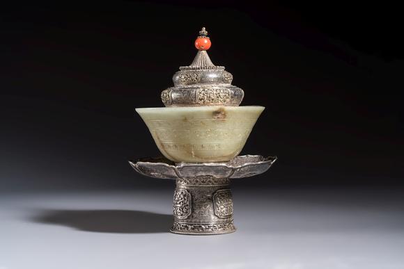 Rob Michiels AuctionsA Tibetan ritual jade bowl with a red coral-mounted silver cover and a stand, 19th C.