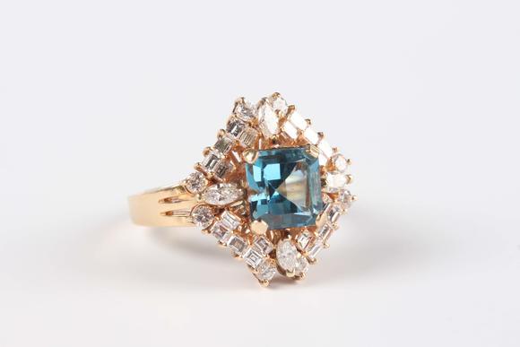 Tooveys|中西方古董藝術(shù)A gold, blue topaz and diamond cluster ring, claw set with the cut cornered square cut blue topaz within a surround of marquise, baguette and circular