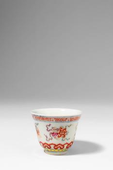 . >
A porcelain cup of slightly flared form, resting on a neatly trimmed foot, and decorated in a