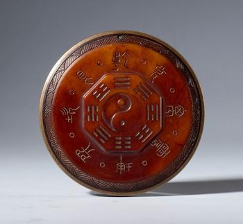 A Hotan red jade plaque with protective Taoist inscriptions. At the center is the symbol of the Tao surrounded by the eight trigrams of the I Ching. China, 19th century