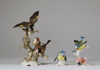 Lot de trois sujets animaliers en porcelaine polychrome figurant des oiseaux branchés, comprenant un groupe de chardonnerets et deux petits oiseaux su