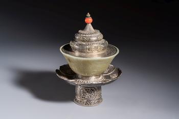 A Tibetan ritual jade bowl with a red coral-mounted silver cover and a stand, 19th C.